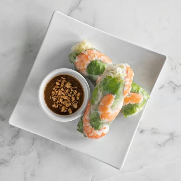 Three fresh Vietnamese spring rolls with shrimp and greens, served with peanut dipping sauce.