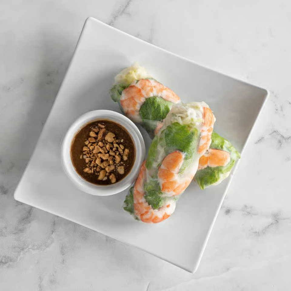 Three fresh Vietnamese spring rolls with shrimp and greens, served with peanut dipping sauce.