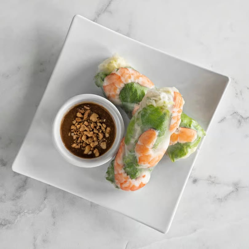 Three fresh Vietnamese spring rolls with shrimp and greens, served with peanut dipping sauce.